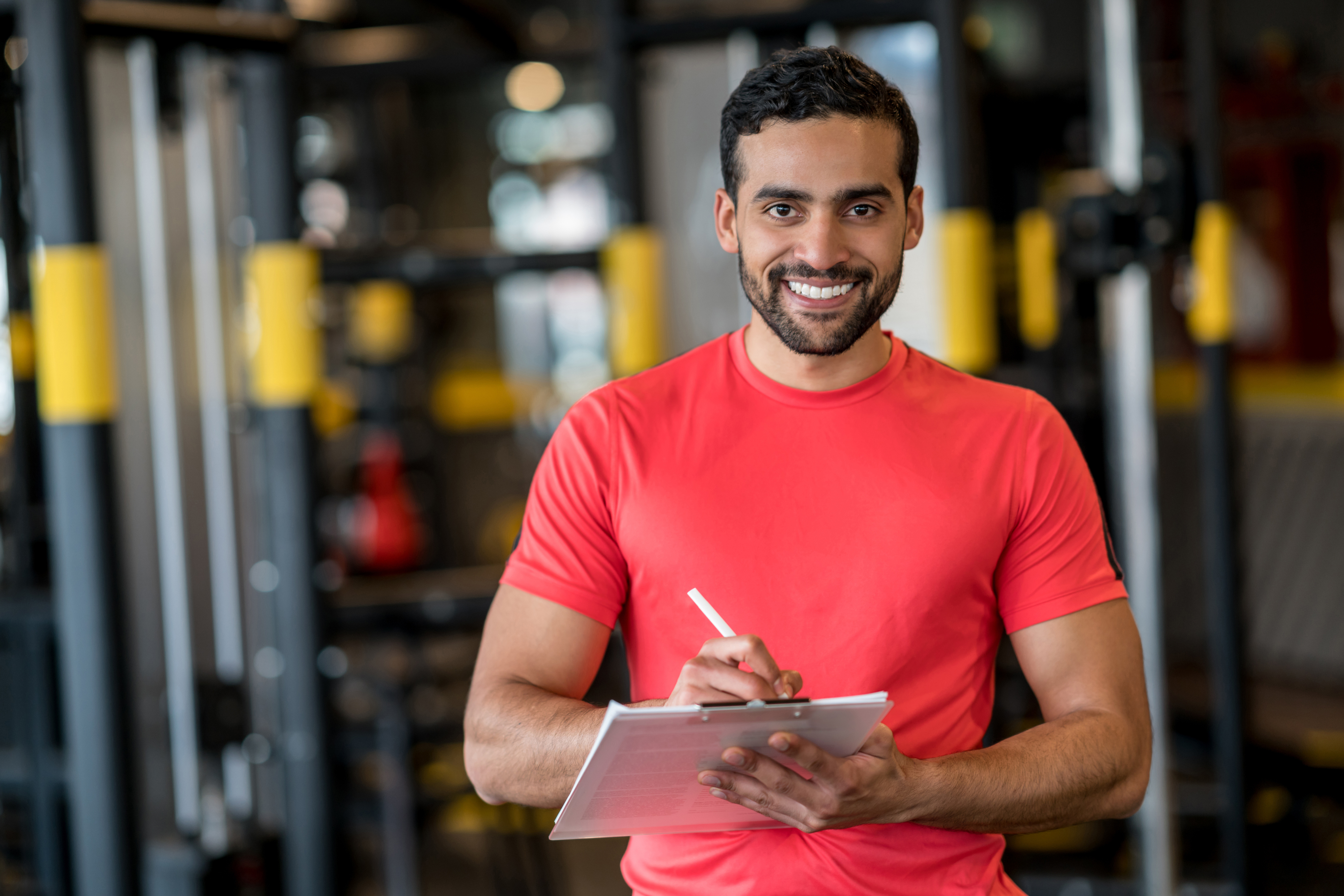 Portrait of a happy personal trainer working at the gym and looking at the camera smiling