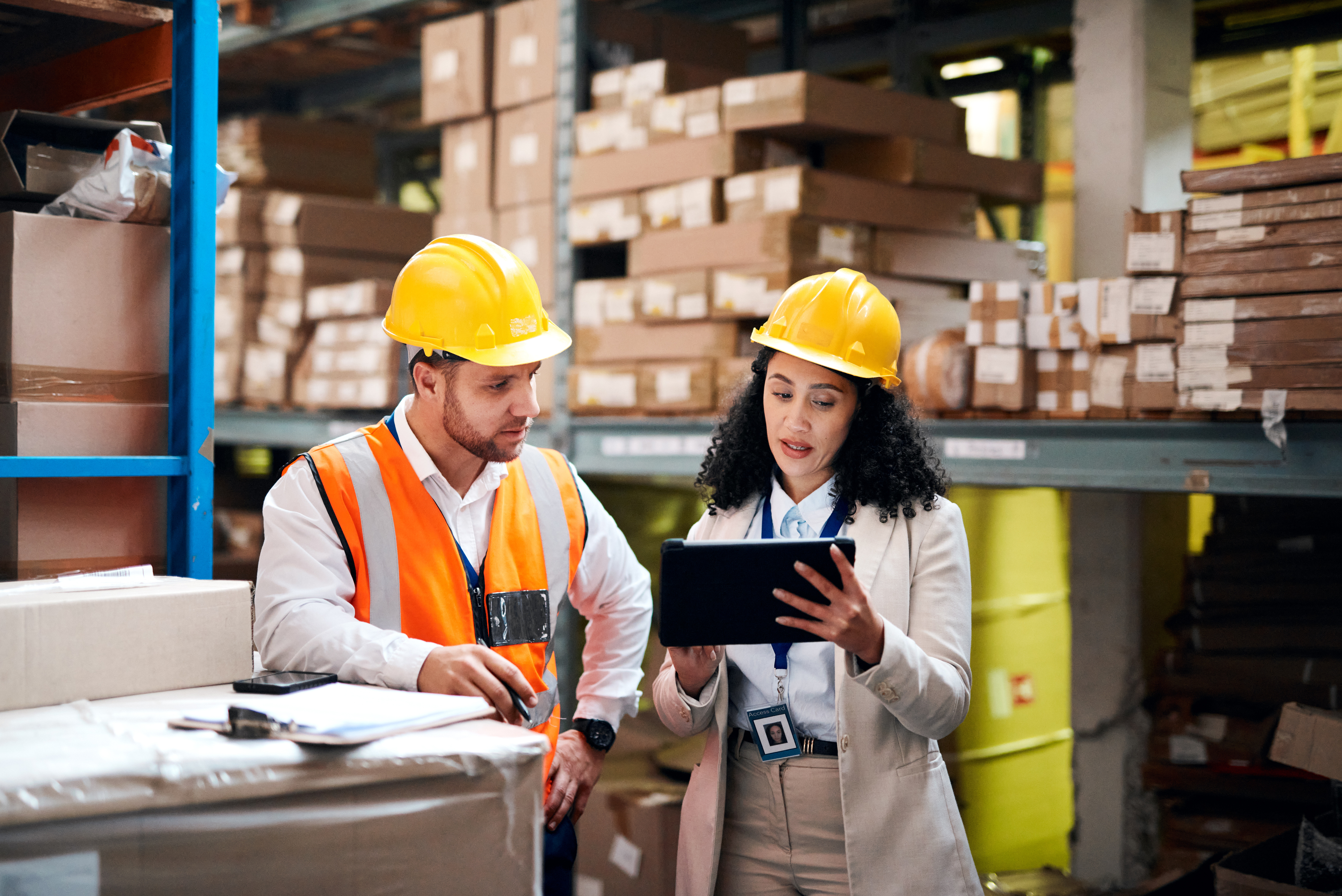 Two people in safety equipment consult a tablet.