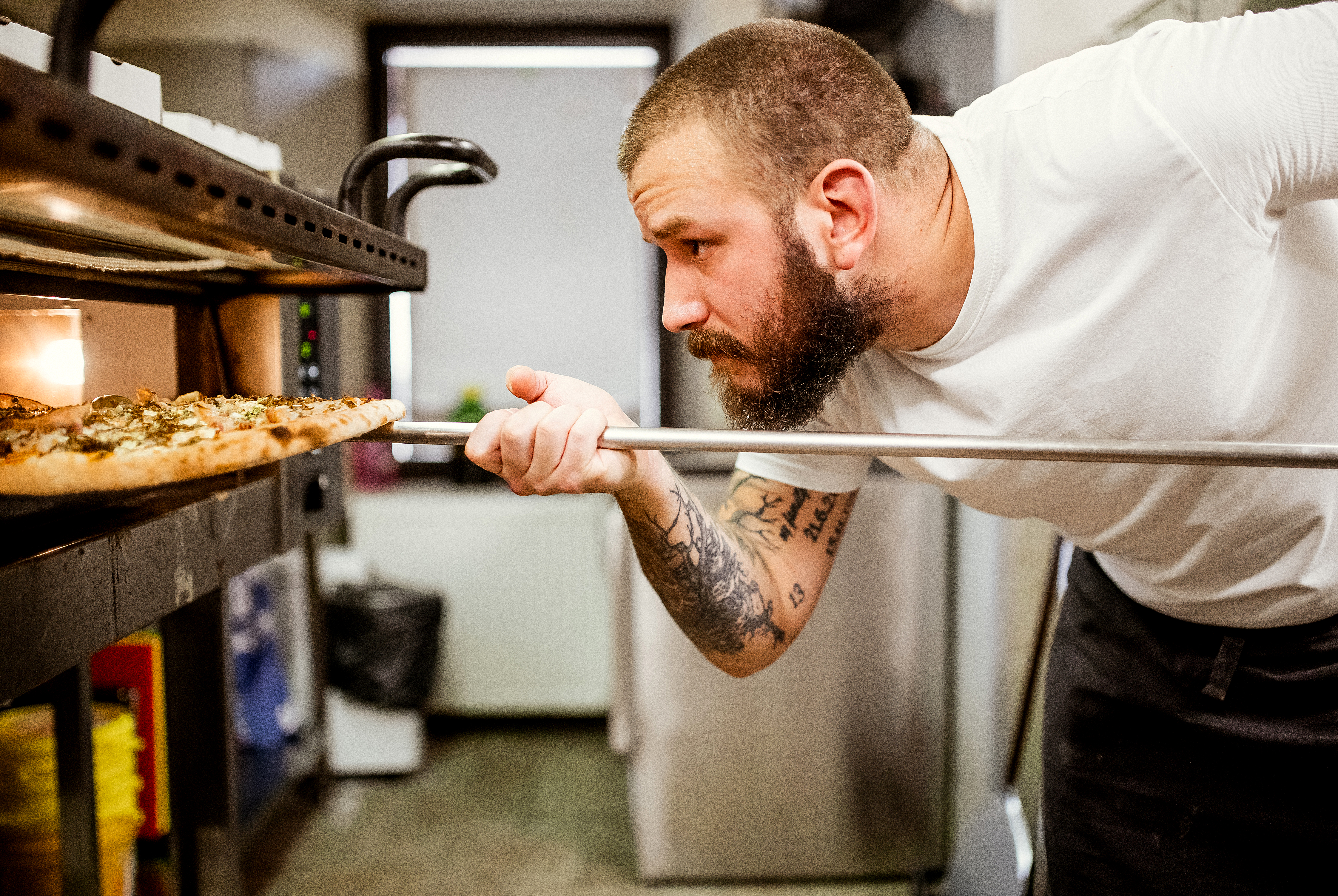 Man putting pizza in an oven