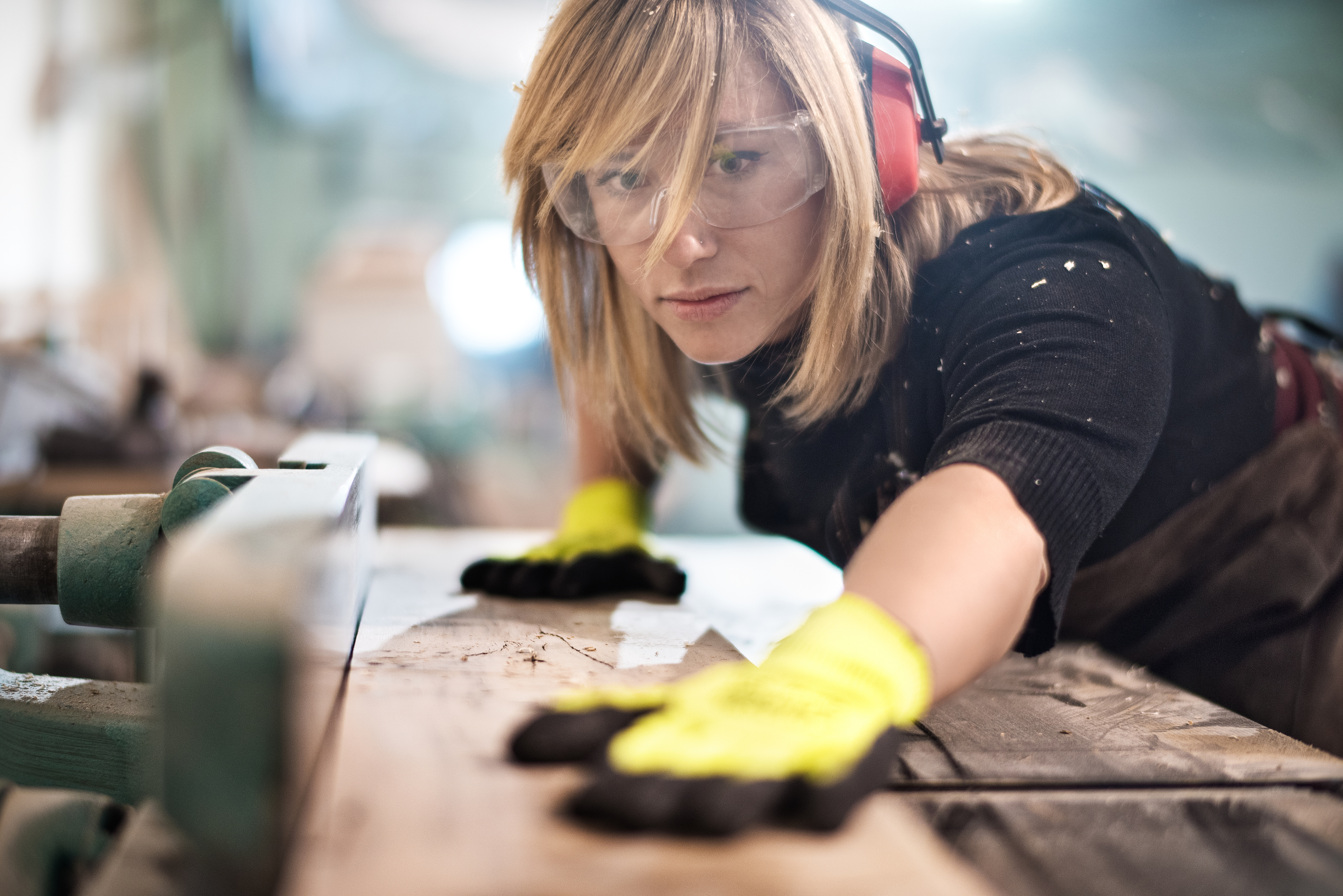 Woman cutting plank of wood using a table saw