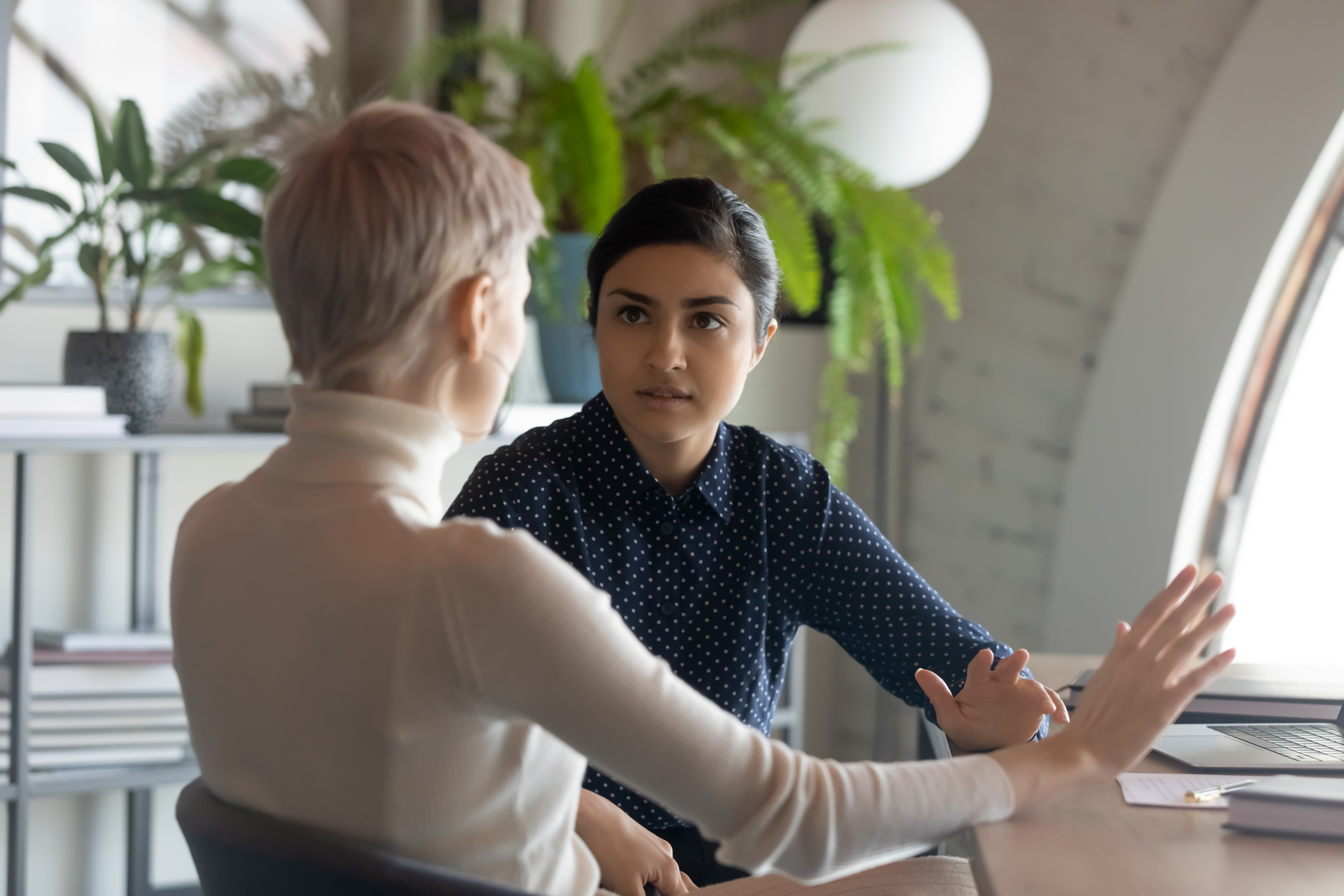 Women having conversation at a desk in the office