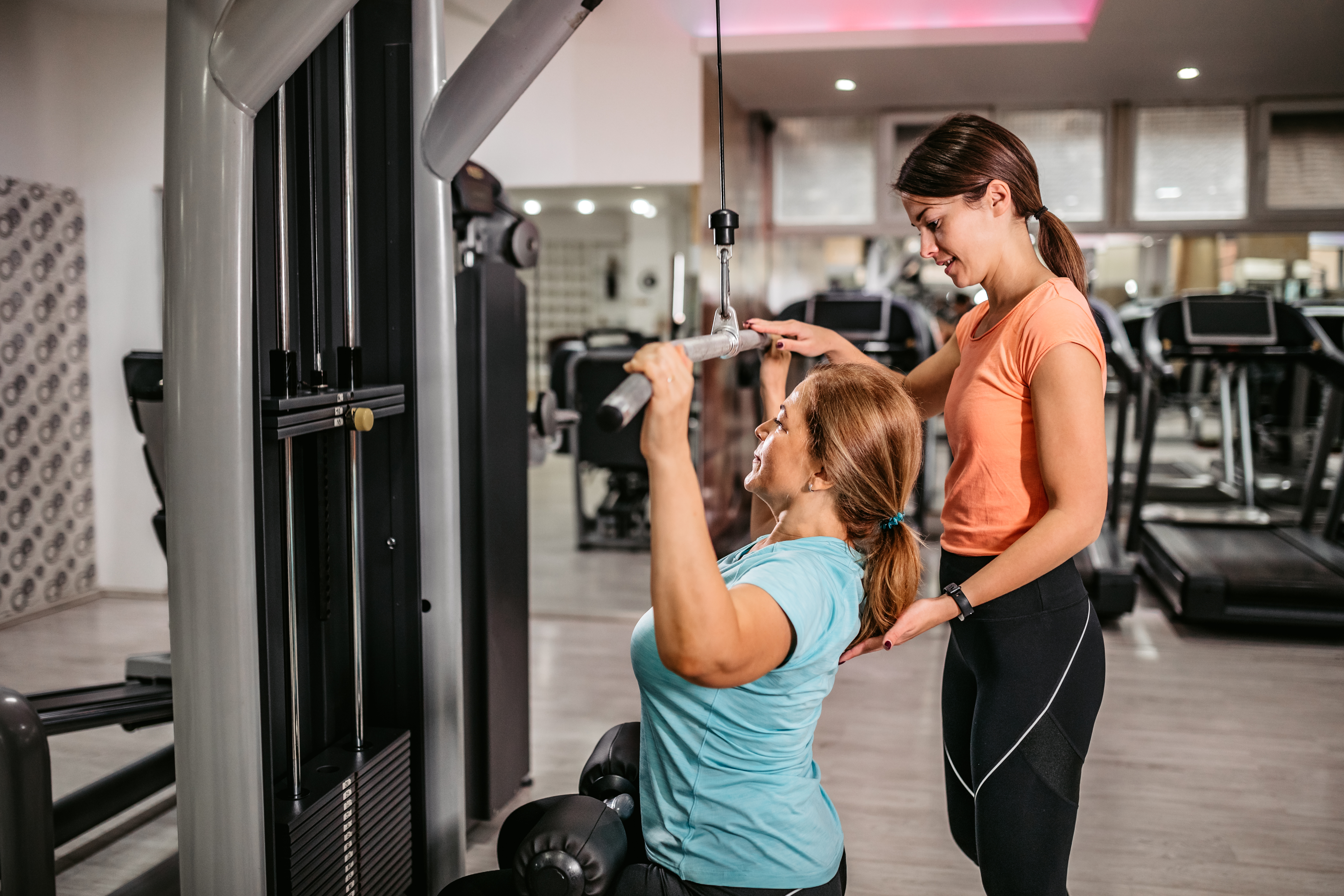 Personal trainer works with client in the gym.