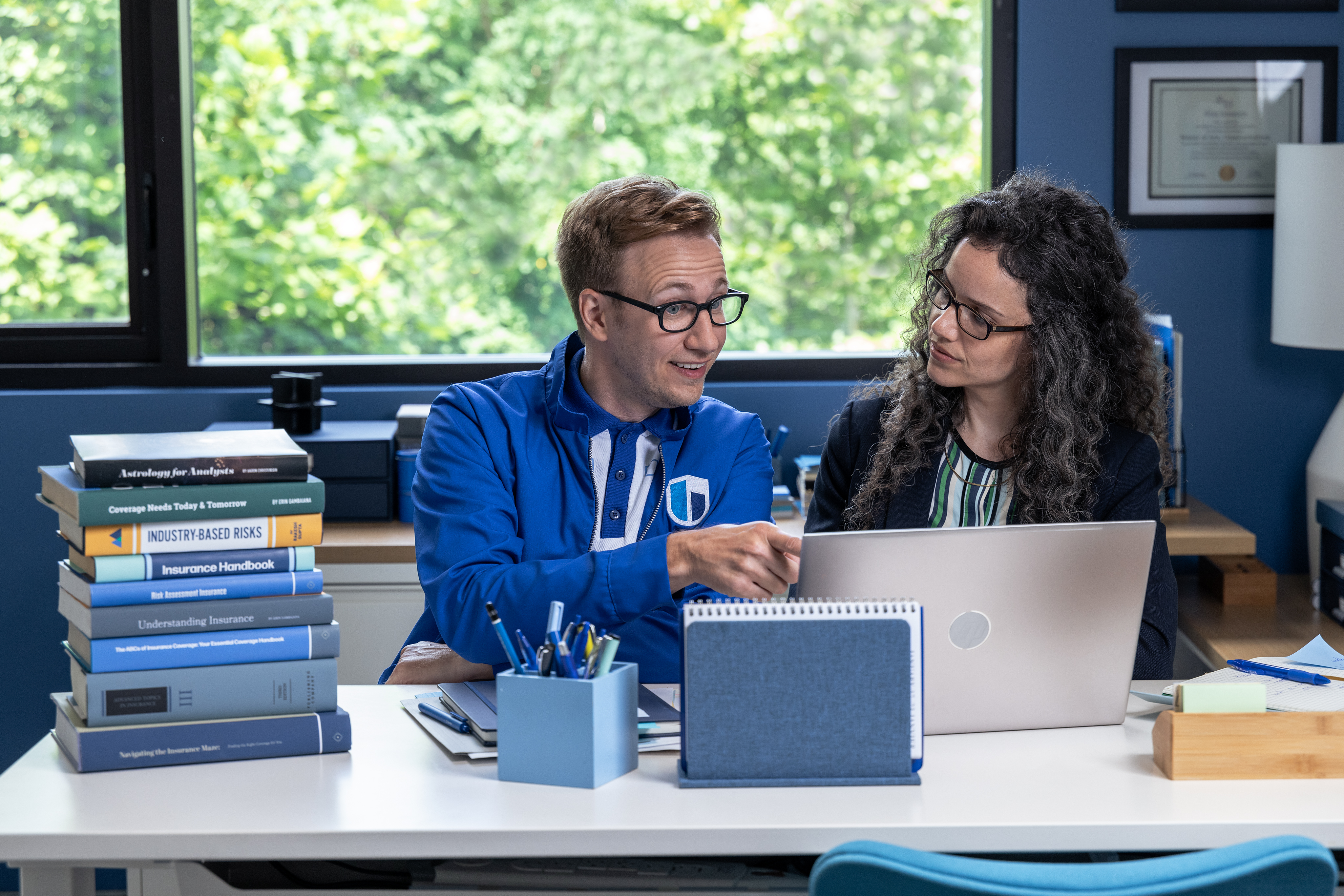 Berk showing office worker something on a laptop computer.
