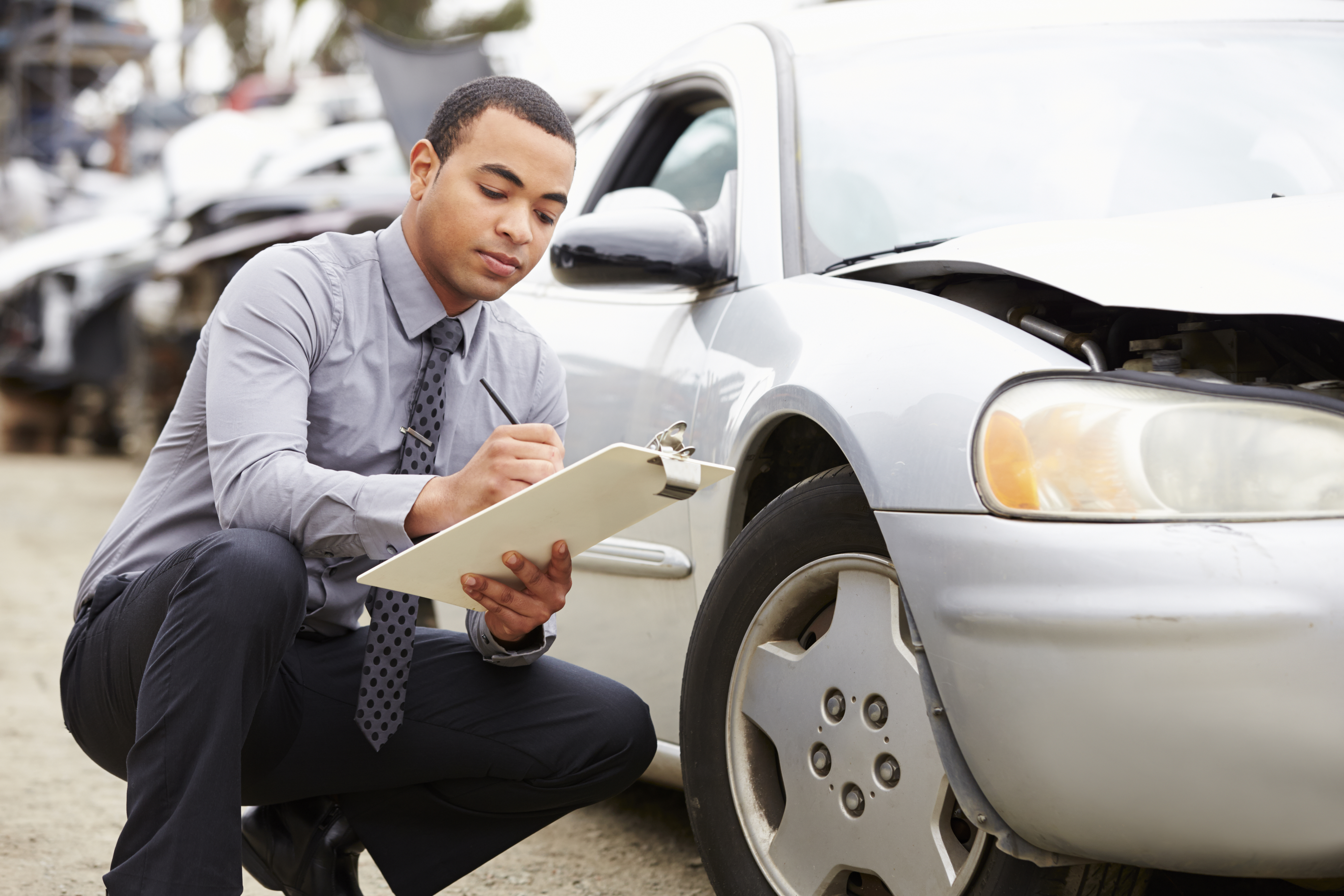 Auto insurance agent adjusting a car