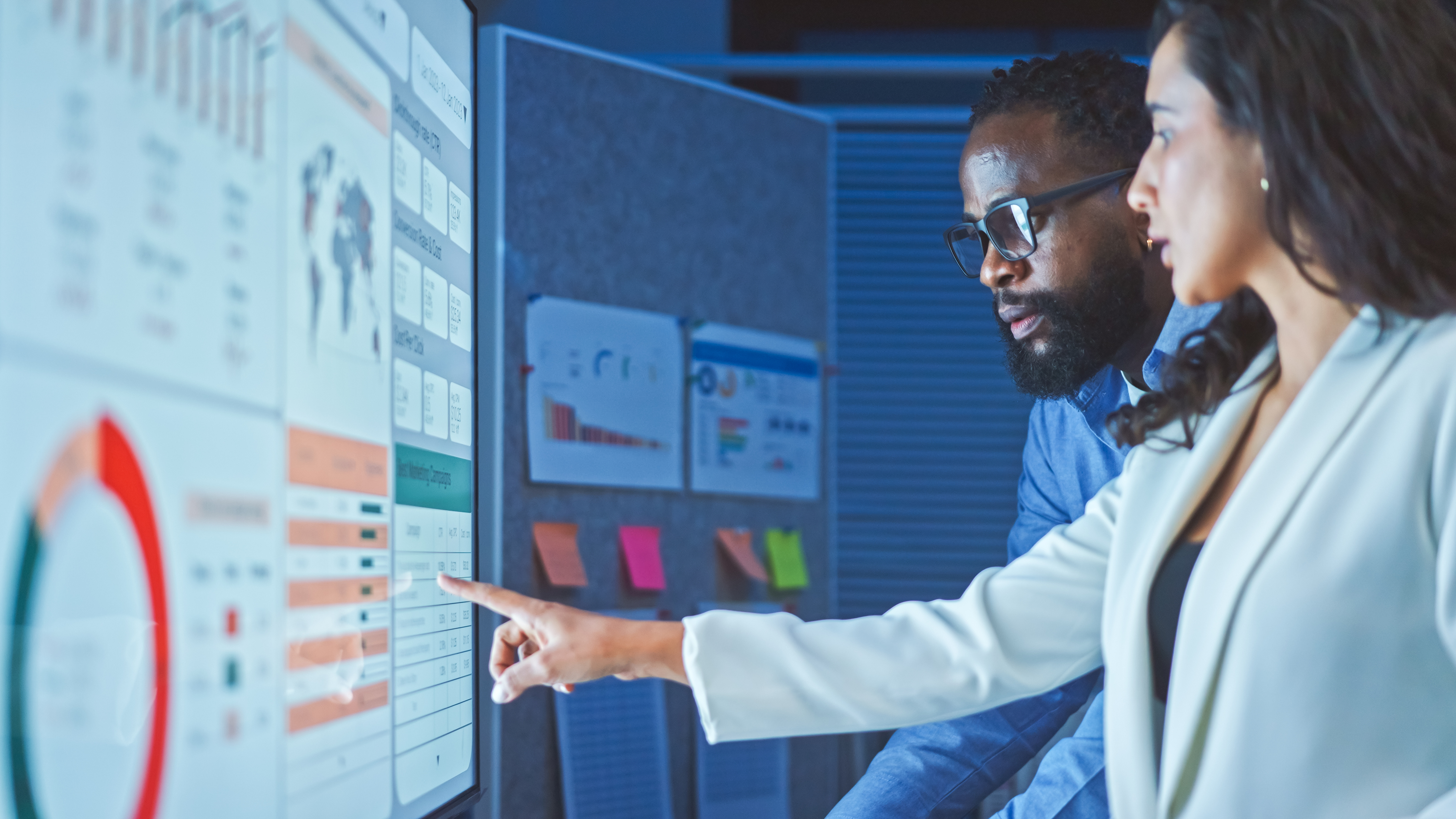 Two employees consulting a technology dashboard